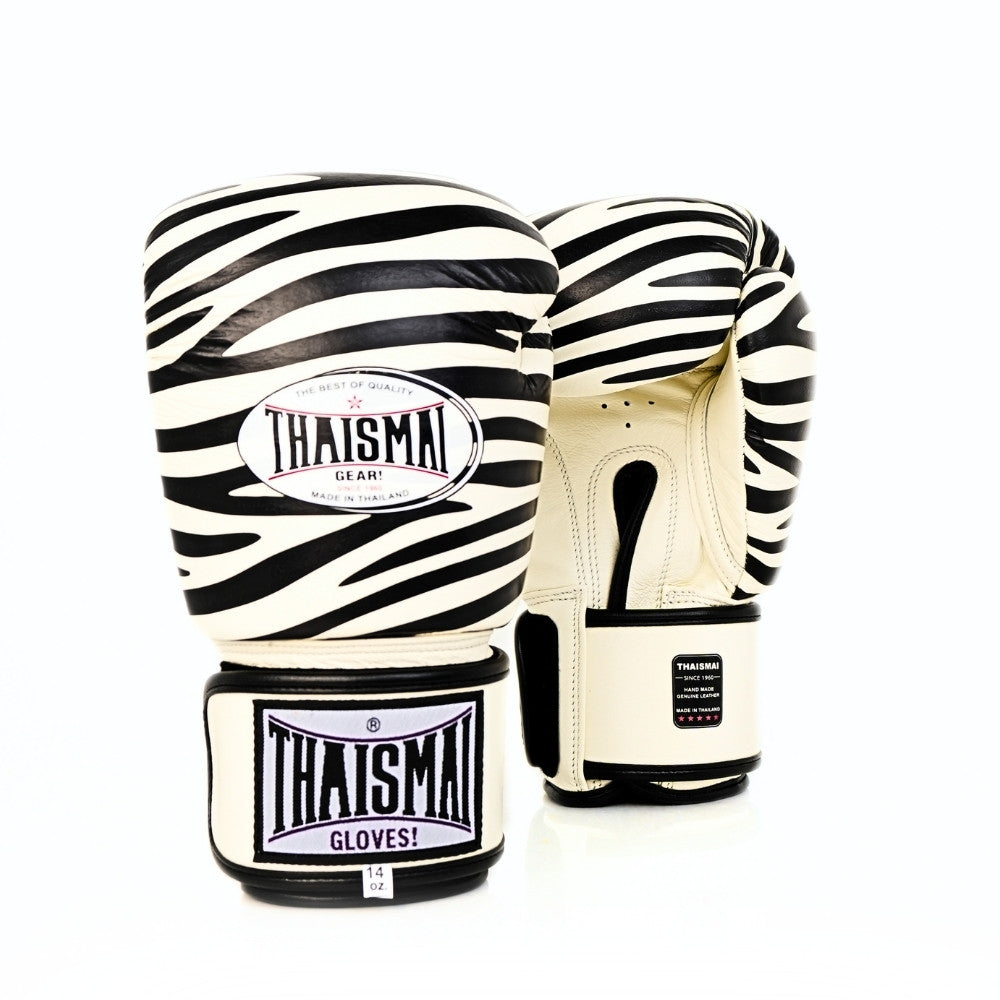 Front view of a pair of white and black ThaiSmai FBG124-Zebra Muay Thai boxing gloves showing the zebra-striped padded knuckles and THAISMAI wrist branding on a white background