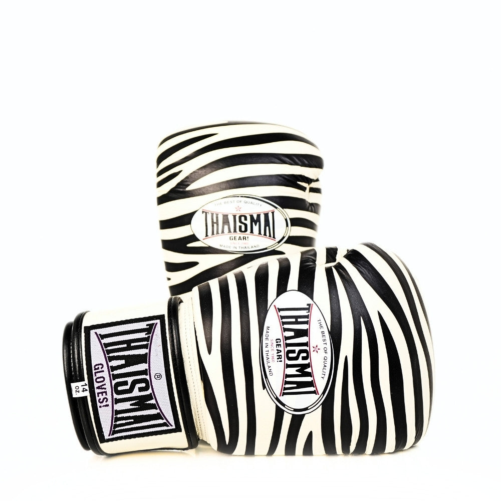 Angled side view of white and black ThaiSmai FBG124-Zebra Muay Thai boxing gloves showing the zebra pattern, padded glove profile and THAISMAI branding on a white background