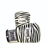 Angled side view of white and black ThaiSmai FBG124-Zebra Muay Thai boxing gloves showing the zebra pattern, padded glove profile and THAISMAI branding on a white background