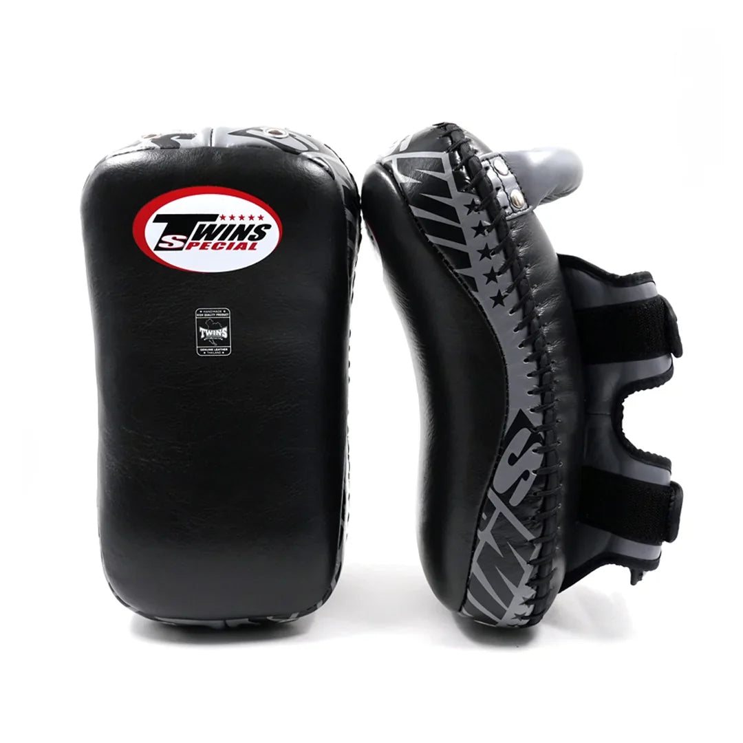Twins Special KPL-12 Deluxe kicking pads in black and gray with dense impact padding, curved striking surface and secure dual-strap hand compartments for Muay Thai and kickboxing training on a white background