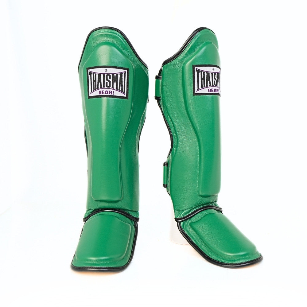 Pair of green THAISMAI LP184 shin guards in a front and angled view, showing the padded shin panels, black trim, foot sections and brand patches against white.