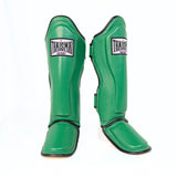 Pair of green THAISMAI LP184 shin guards in a front and angled view, showing the padded shin panels, black trim, foot sections and brand patches against white.