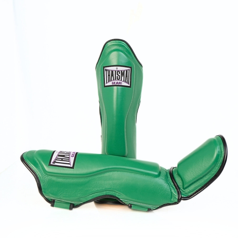 Angled view of green THAISMAI LP184 shin guards showing the shin shells, curved foot pads, side profile and black fastening straps against white.