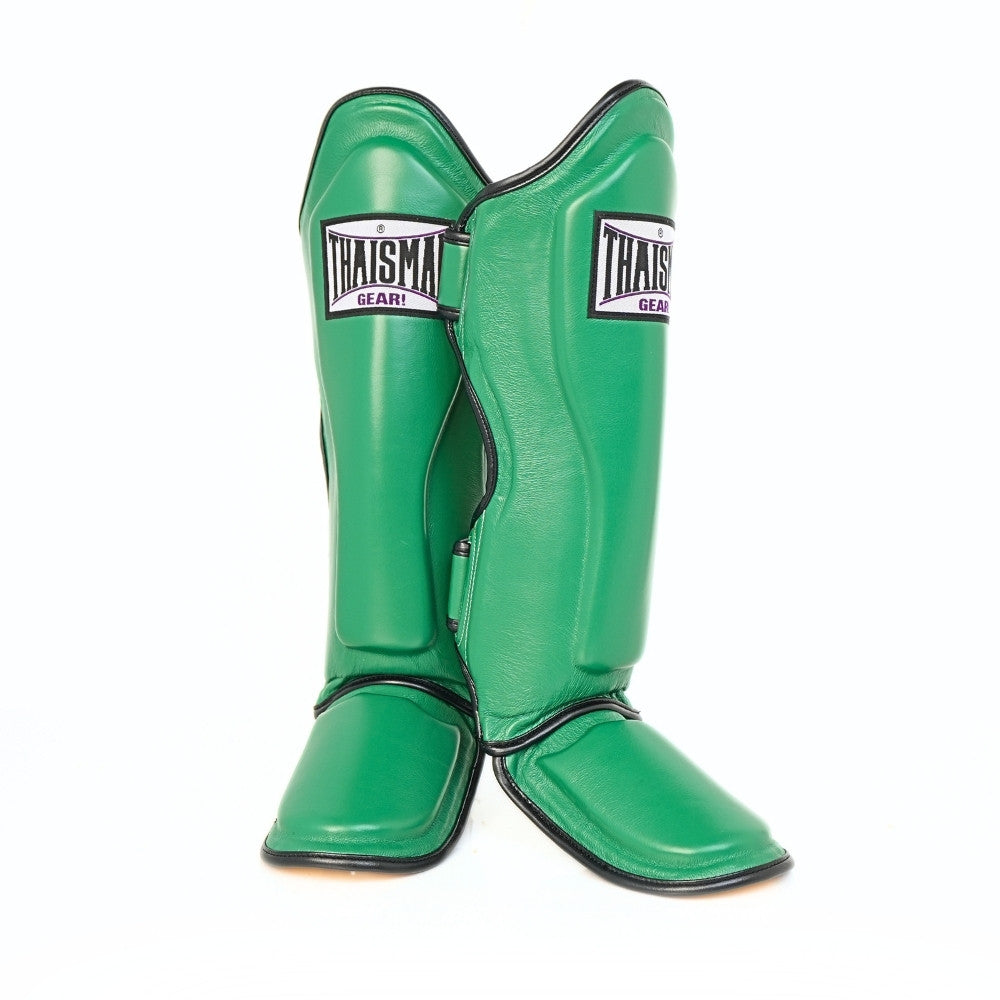 Pair of green THAISMAI LP184 Muay Thai shin guards shown overlapping in a front view, highlighting their contoured padded shells, foot protection and black edge trim.