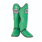 Pair of green THAISMAI LP184 Muay Thai shin guards shown overlapping in a front view, highlighting their contoured padded shells, foot protection and black edge trim.