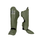 Top King TKSGP-GL Pro shin guards in black genuine leather with full-length shin and instep protection, dense impact padding and secure hook-and-loop closures for Muay Thai and kickboxing on a white background