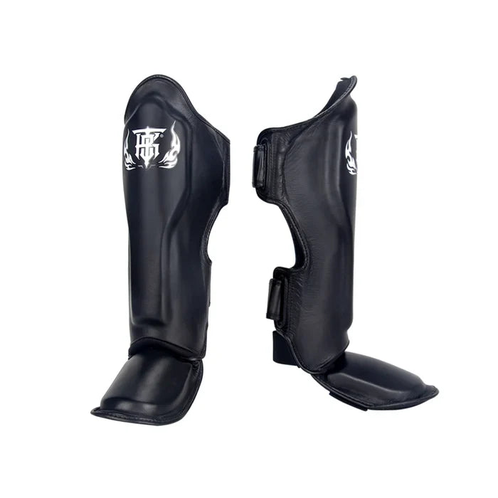 Top King TKSGP-GL Pro shin guards in black genuine leather with full-length shin and instep protection, dense impact padding and secure hook-and-loop closures for Muay Thai and kickboxing on a white background