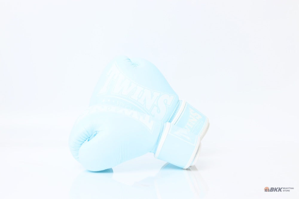 Single light blue Twins Special boxing glove with white branding and hook-and-loop wrist closure resting on a reflective white surface