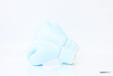 Single light blue Twins Special boxing glove with white branding and hook-and-loop wrist closure resting on a reflective white surface
