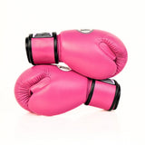 Pink THAISMAI BG124 boxing gloves crossed on a white background, showing the black wrist cuffs, padded striking surfaces and partially visible glove logos.