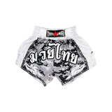 Back view of THAISMAI Muay Thai shorts in black, grey and white digital camouflage with white side panels, elastic waistband, Thai script and THAISMAI branding on a white background