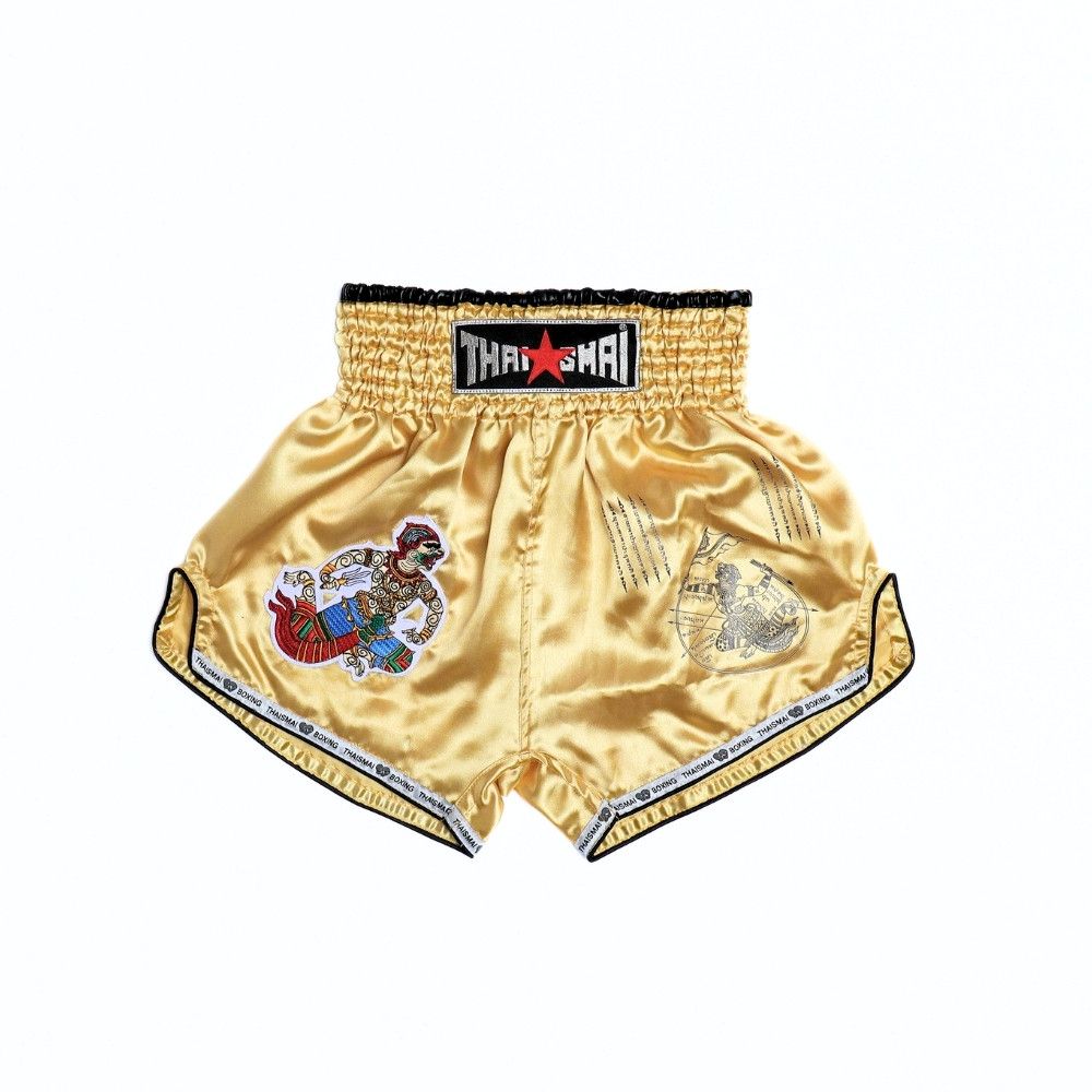 Front view of gold THAISMAI BS-HANUMAN Muay Thai shorts showing the elastic waistband, colorful Hanuman warrior embroidery, sacred-style artwork and black trim on a white background