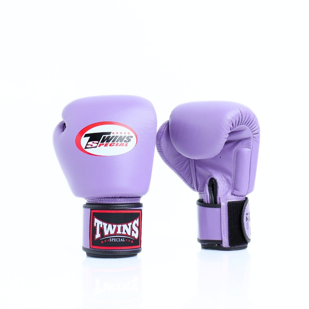 Pair of lavender Twins Special boxing gloves showing the front logo and rear glove with black wrist strap and branded wrist patch on a white background