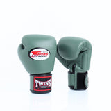 Pair of olive green Twins Special boxing gloves showing the front logo and rear glove with black hook-and-loop wrist strap and branded wrist patch on a white background