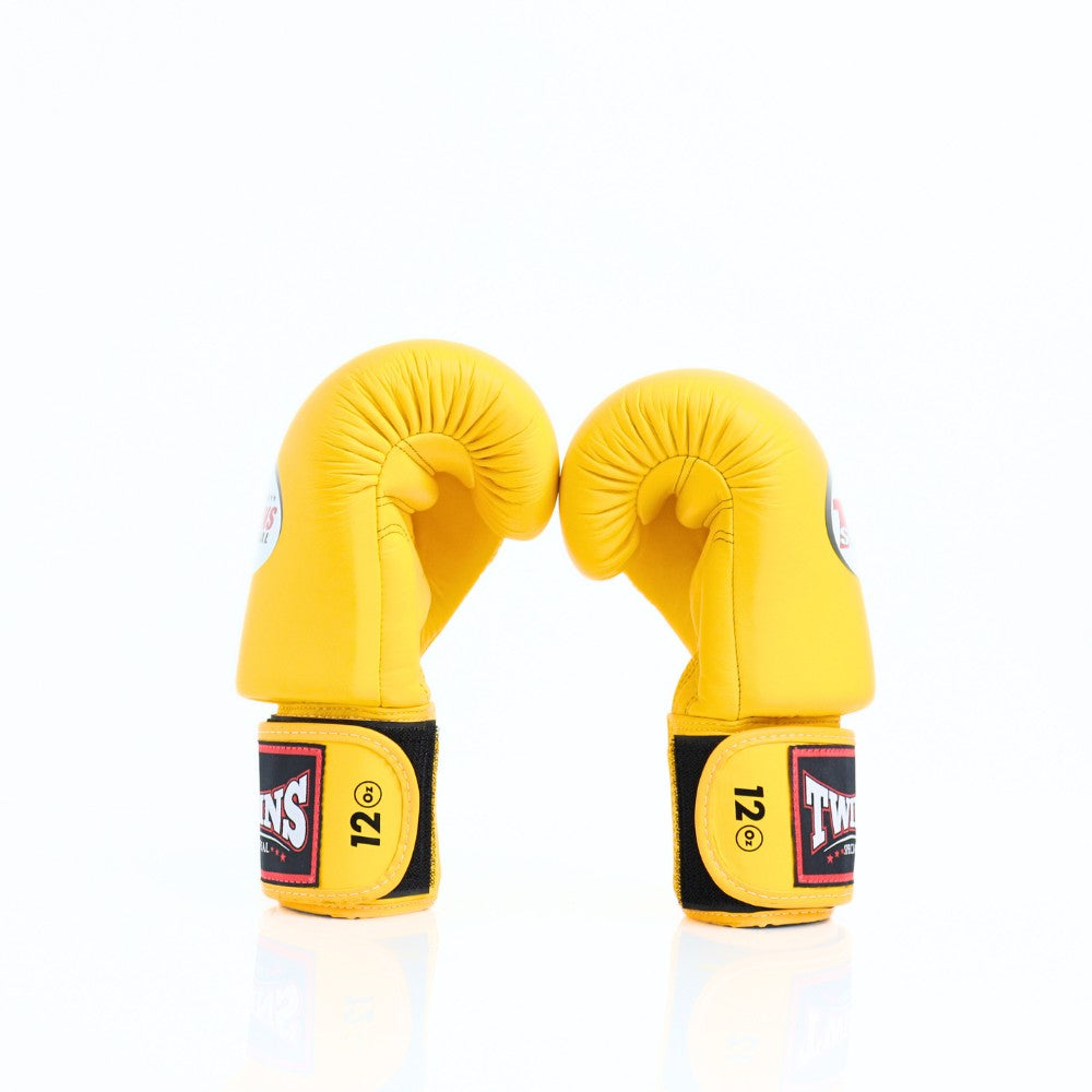 Pair of yellow Twins Special boxing gloves with black accents, 12 oz markings and branded wrist patches displayed on a white background