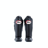 Twins Special SGL-10 shin guards in black synthetic leather with full-length shin and instep protection, secure hook-and-loop straps and padded support for Muay Thai and kickboxing training on a white background