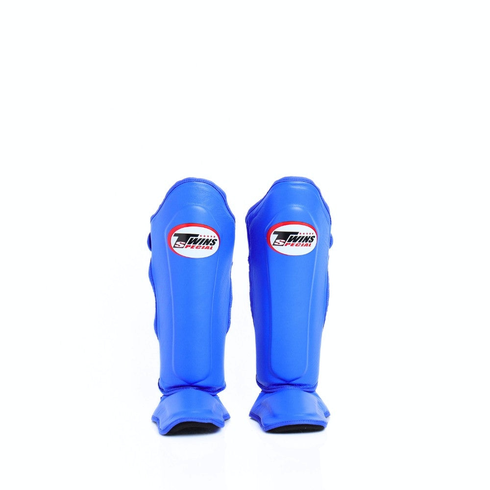 Twins Special SGL-10 shin guards in black synthetic leather with full-length shin and instep protection, secure hook-and-loop straps and padded support for Muay Thai and kickboxing training on a white background