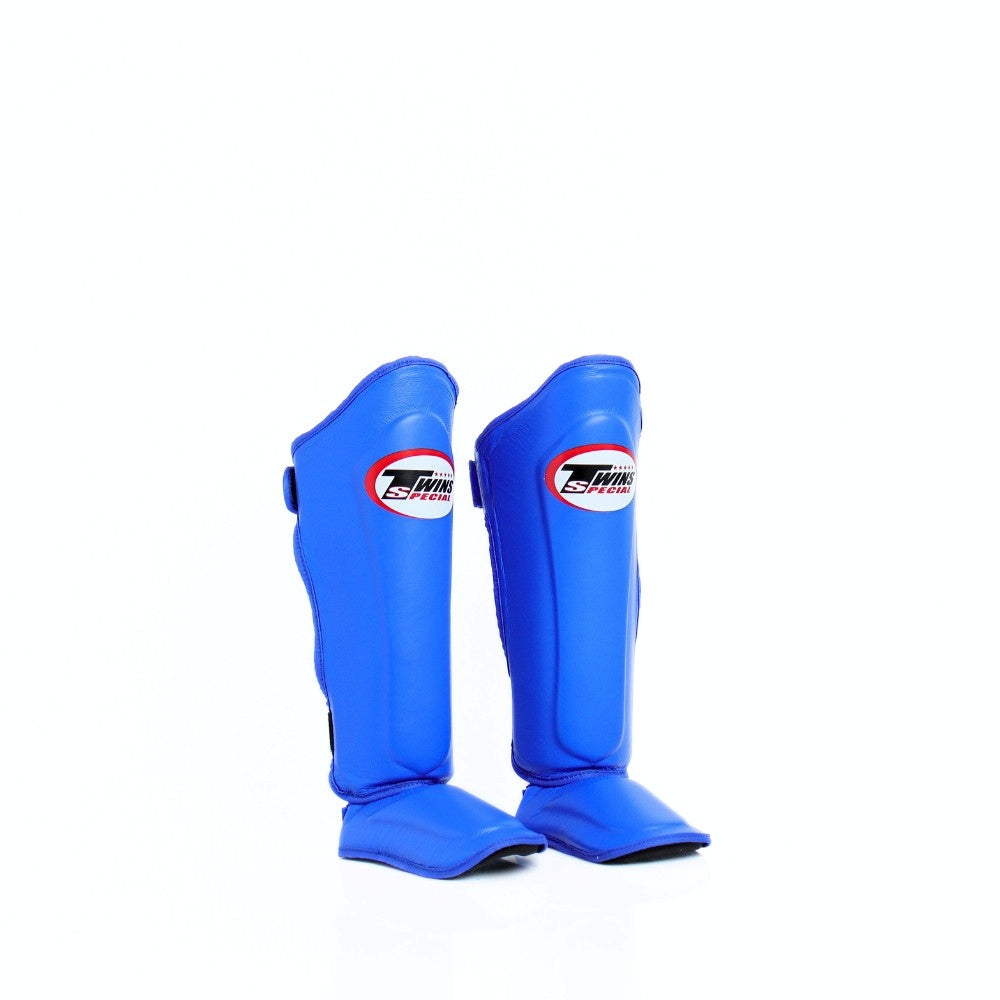 Twins Special SGL-10 shin guards in black synthetic leather with full-length shin and instep protection, secure hook-and-loop straps and padded support for Muay Thai and kickboxing training on a white background