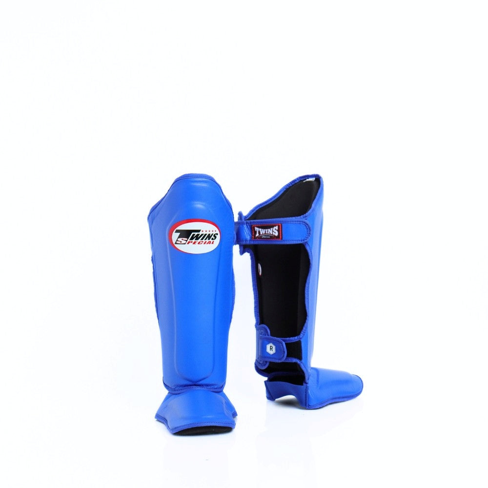 Twins Special SGL-10 shin guards in black synthetic leather with full-length shin and instep protection, secure hook-and-loop straps and padded support for Muay Thai and kickboxing training on a white background