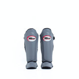 Twins Special SGL-10 shin guards in black synthetic leather with full-length shin and instep protection, secure hook-and-loop straps and padded support for Muay Thai and kickboxing training on a white background