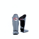 Twins Special SGL-10 shin guards in black synthetic leather with full-length shin and instep protection, secure hook-and-loop straps and padded support for Muay Thai and kickboxing training on a white background