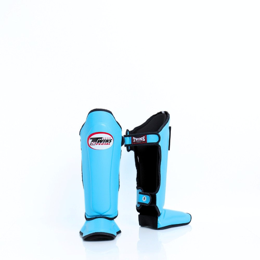Twins Special SGL-10 shin guards in black synthetic leather with full-length shin and instep protection, secure hook-and-loop straps and padded support for Muay Thai and kickboxing training on a white background