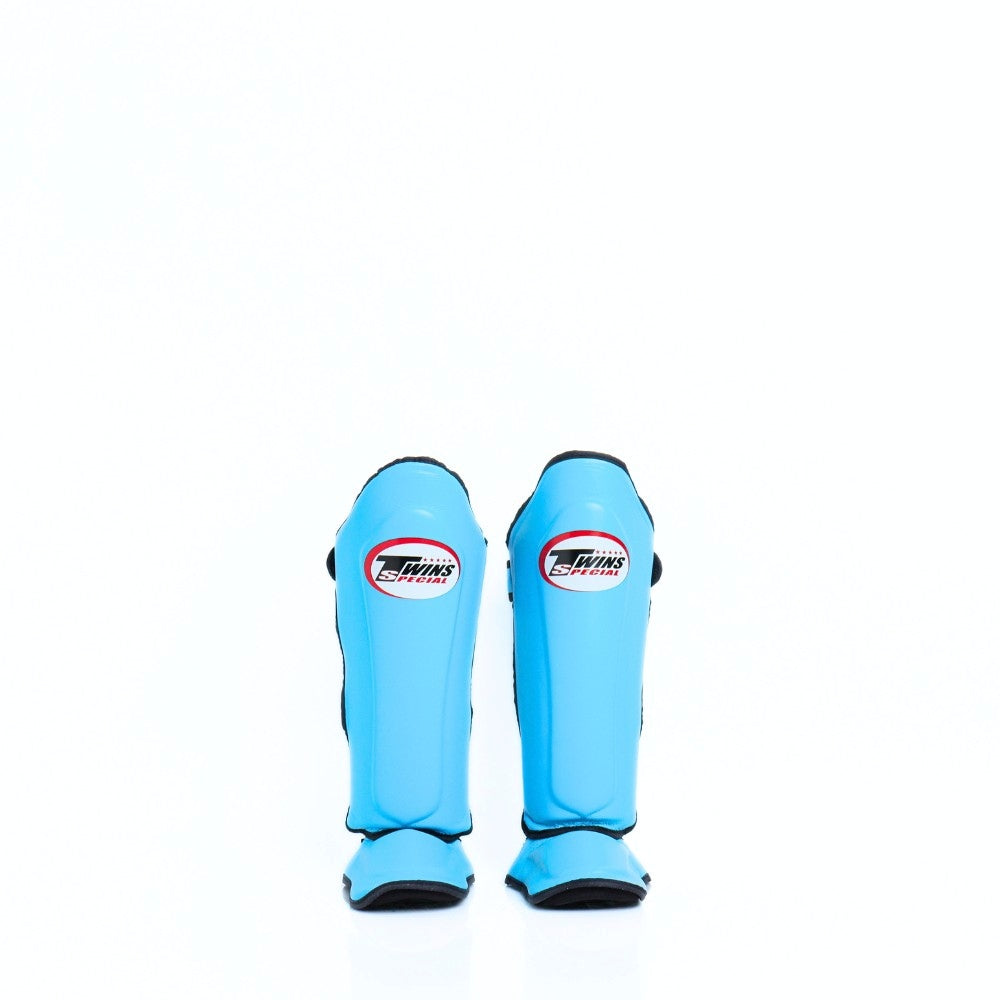 Twins Special SGL-10 shin guards in black synthetic leather with full-length shin and instep protection, secure hook-and-loop straps and padded support for Muay Thai and kickboxing training on a white background