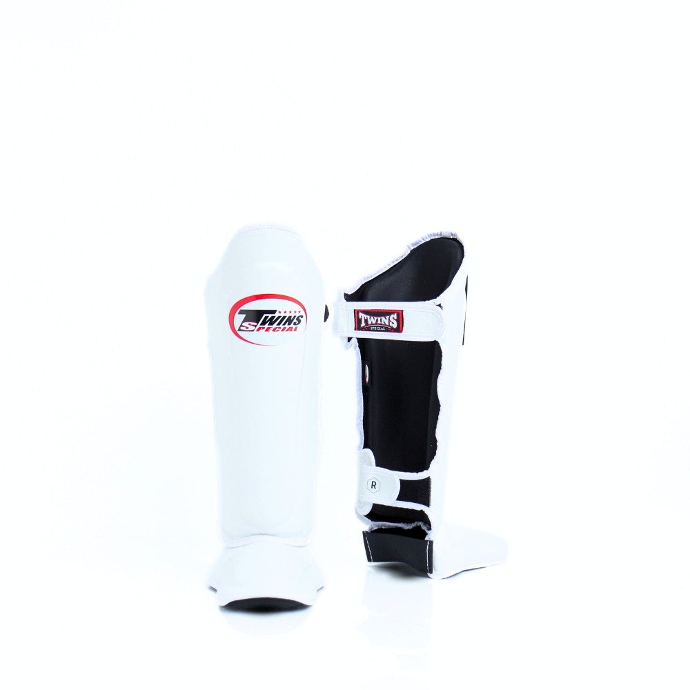 Twins Special SGL-10 shin guards in black synthetic leather with full-length shin and instep protection, secure hook-and-loop straps and padded support for Muay Thai and kickboxing training on a white background