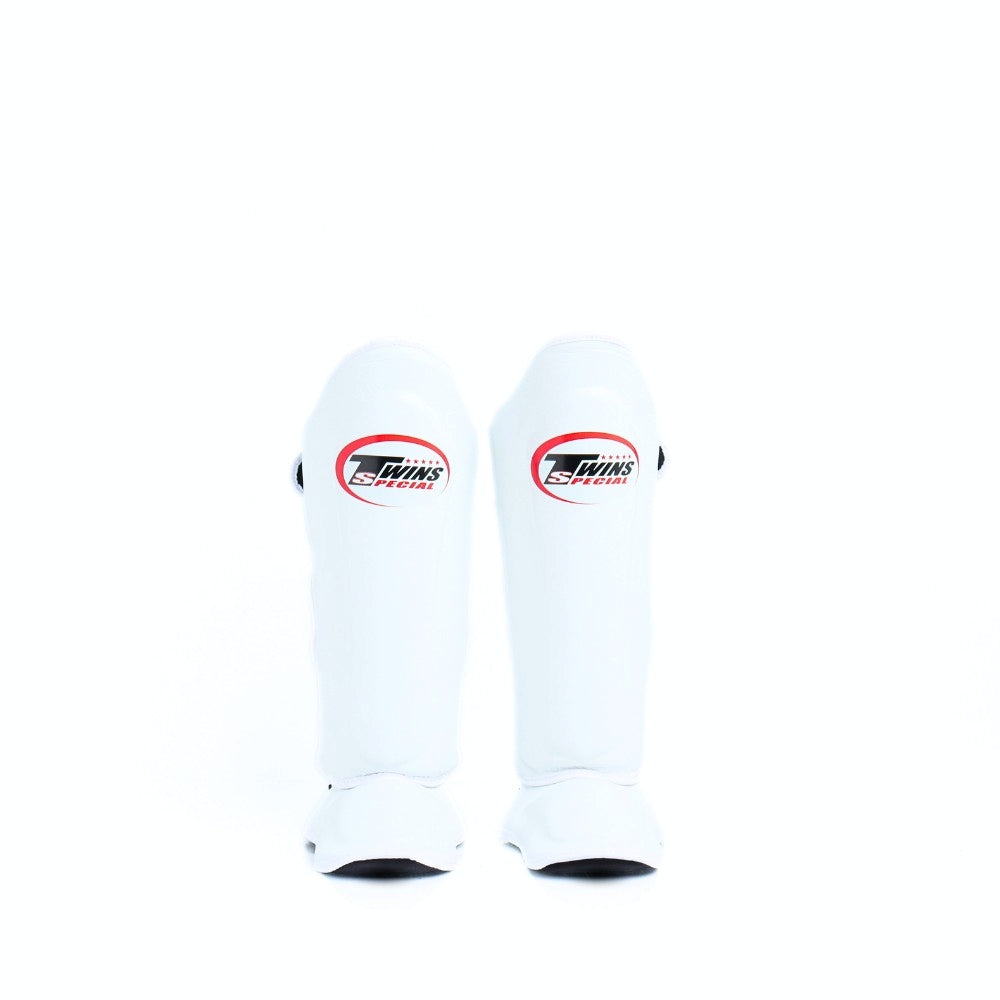 Twins Special SGL-10 shin guards in black synthetic leather with full-length shin and instep protection, secure hook-and-loop straps and padded support for Muay Thai and kickboxing training on a white background