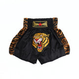 Front view of black and yellow ThaiSmai TIGER Muay Thai shorts with bold tiger artwork, elastic waistband and traditional side-slit cut on a white background