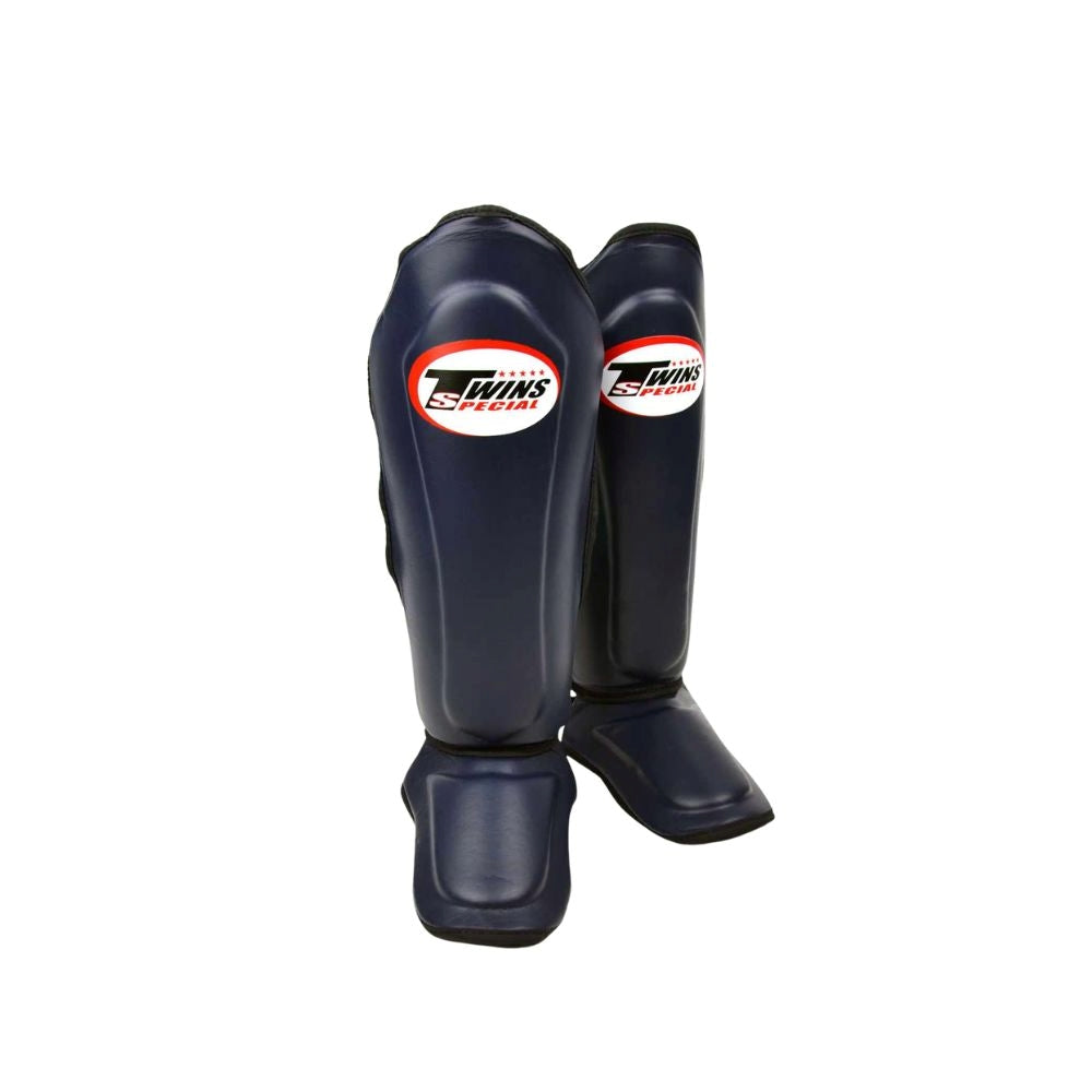 Twins Special SGL-10 shin guards in black synthetic leather with full-length shin and instep protection, secure hook-and-loop straps and padded support for Muay Thai and kickboxing training on a white background