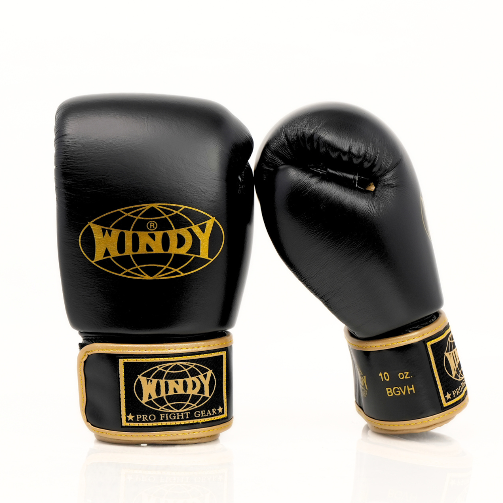 Side view of Windy BGVH black and gold Muay Thai boxing gloves showing the padded glove profile, thumb guard and extended wrist cuff on a white background