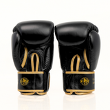 Angled view of Windy BGVH black and gold Muay Thai boxing gloves showing padded knuckles, thumb guard, leather construction and secure wrist closure on a white background