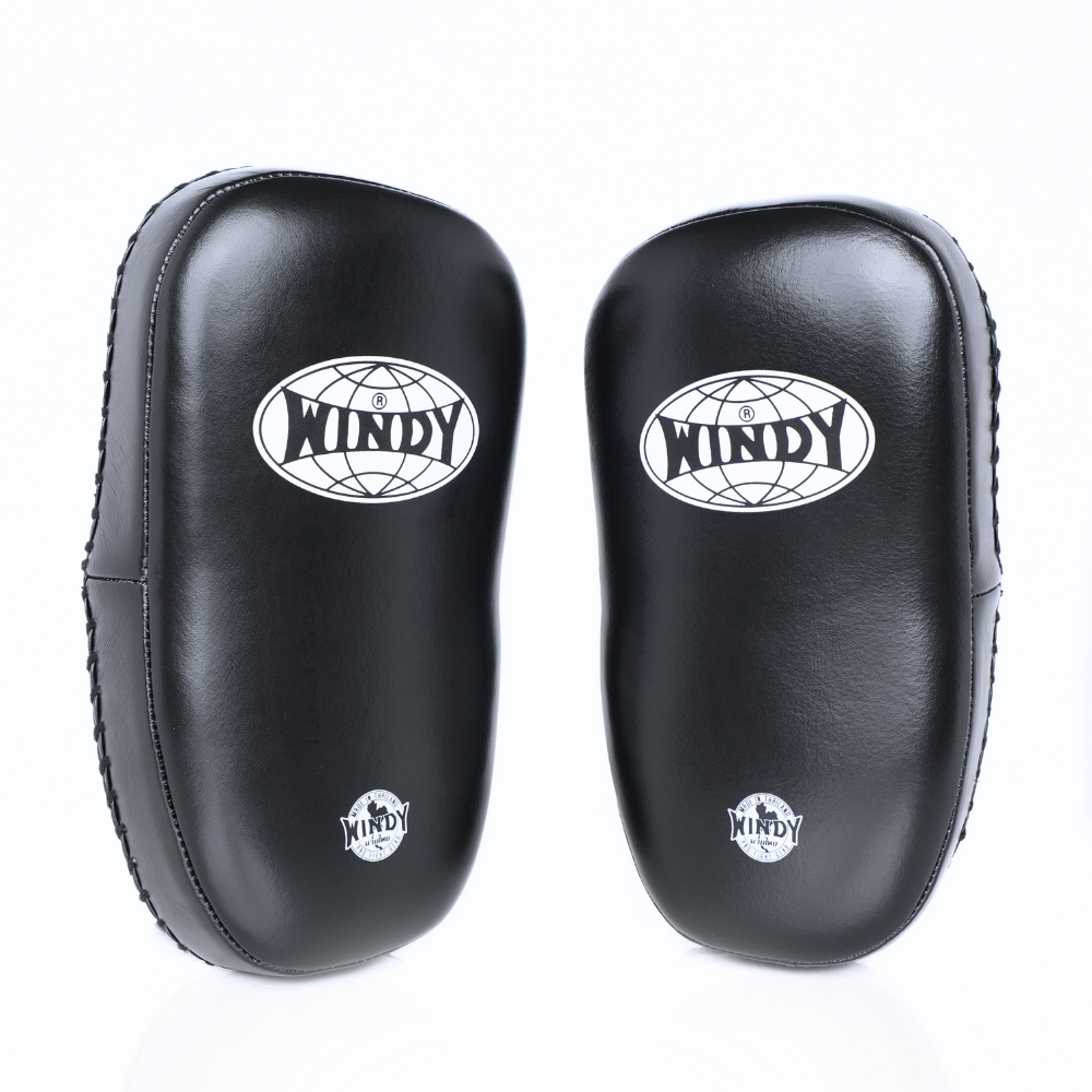 Angled side view of black Windy KP-8 leather kick pads showing single straps, thick curved padding and stitched leather edges on a white background