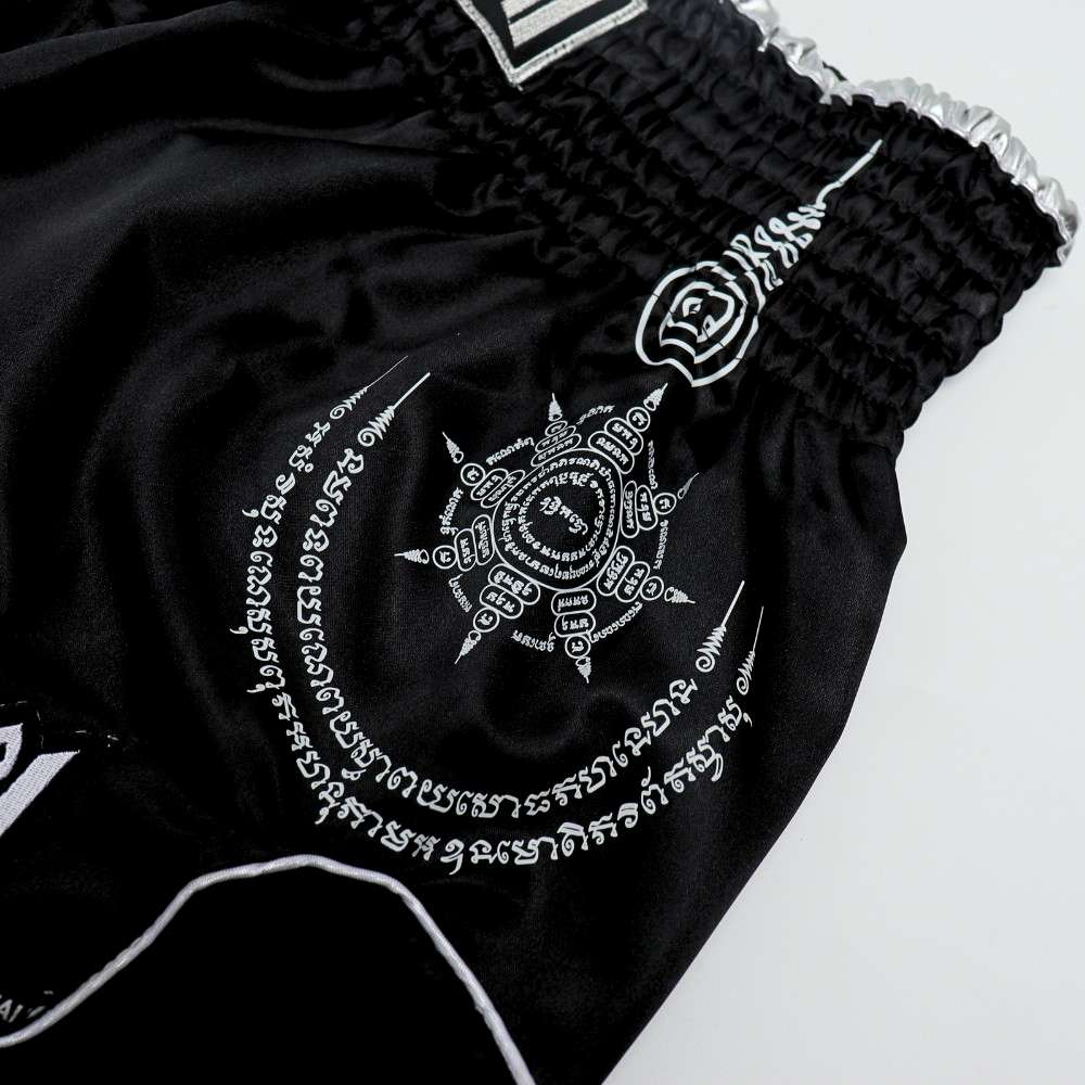 THAISMAI SAK YANT Muay Thai boxing shorts in lightweight satin with Thai lettering, classic side-slit cut and traditional fightwear design on a white background